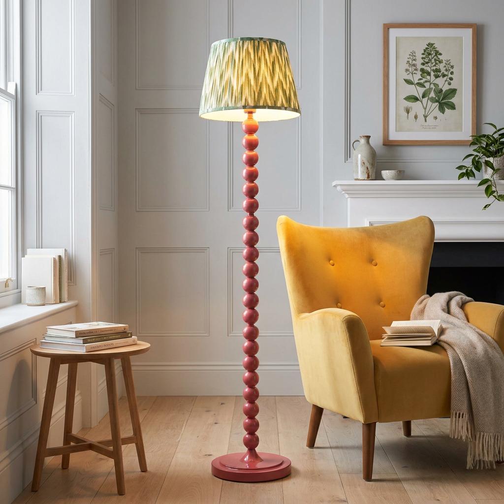 Higgledy pink floor lamp with a Cotswold green zigzag shade standing next to a yellow velvet armchair.