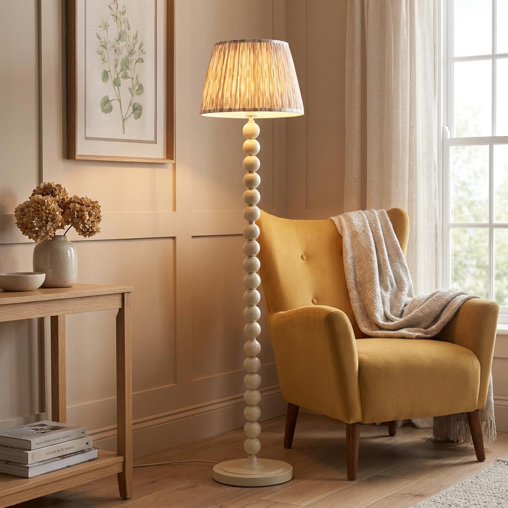 A white beaded floor lamp with a neutral ikat shade stands next to a yellow armchair in a cozy living room.
