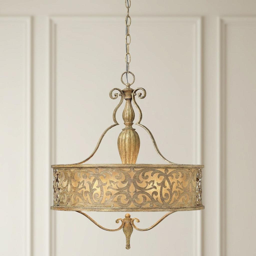 Ornate brushed champagne pendant light featuring a scrollwork metal drum shade hanging against a white paneled wall.