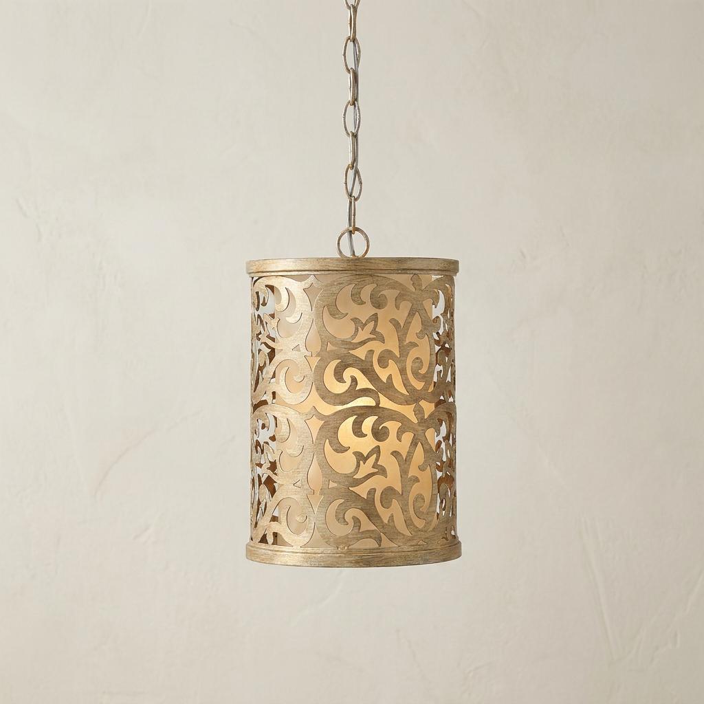 Brushed champagne cylinder pendant light with an ornate scrollwork cutout pattern hanging by a chain.