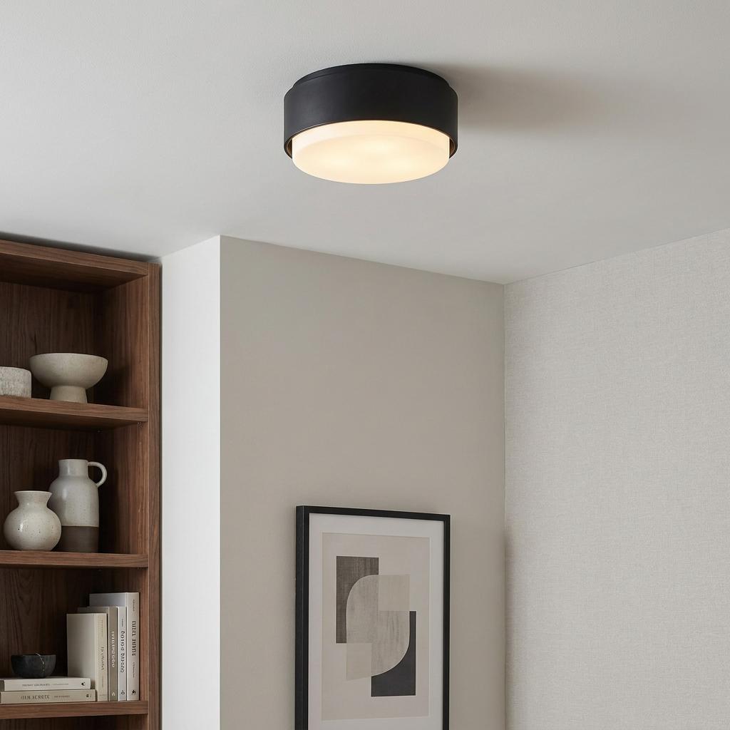Modern black flush ceiling light with illuminated white shade mounted in a neutral living space.