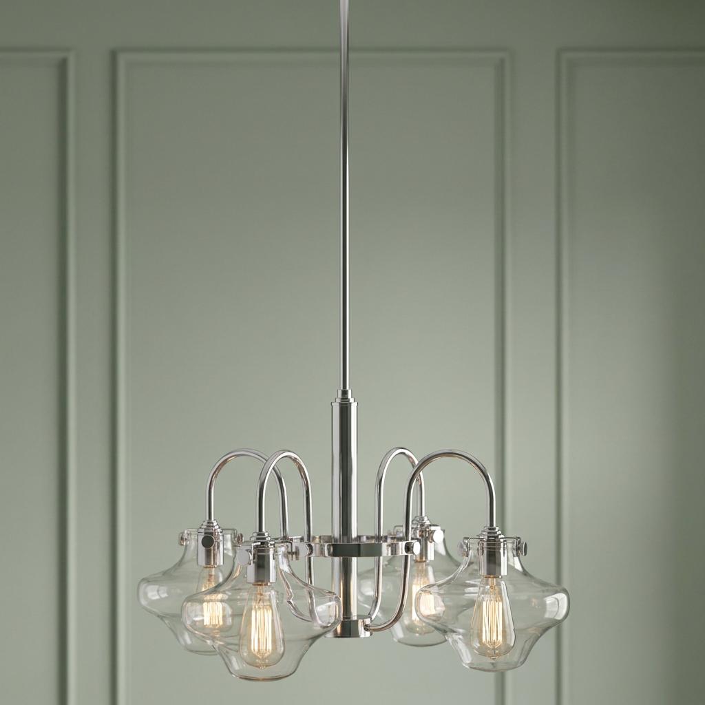 Chrome 4-light chandelier with clear vintage-style glass shades and bulbs against a soft green paneled wall.