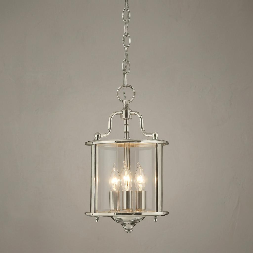 Hinkley Gentry 3-light polished nickel lantern pendant with clear glass and candle-style bulbs against a neutral wall.