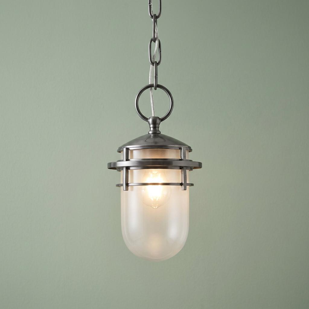 Nautical-style pendant light with a hematite cage and frosted glass shade, lit against a soft green background.