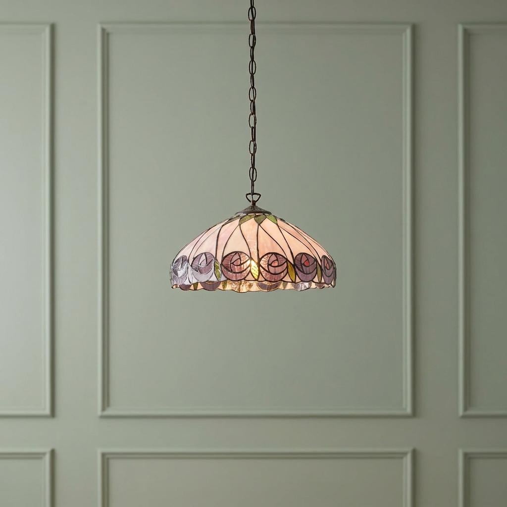 Tiffany style ceiling pendant with a pink rose stained glass shade, hanging against a green paneled wall.