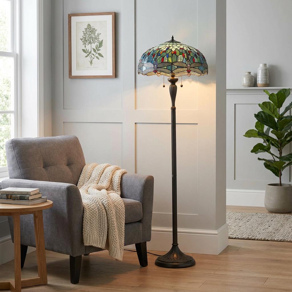 Blue dragonfly Tiffany floor lamp illuminated next to a grey armchair in a cozy, modern living room.
