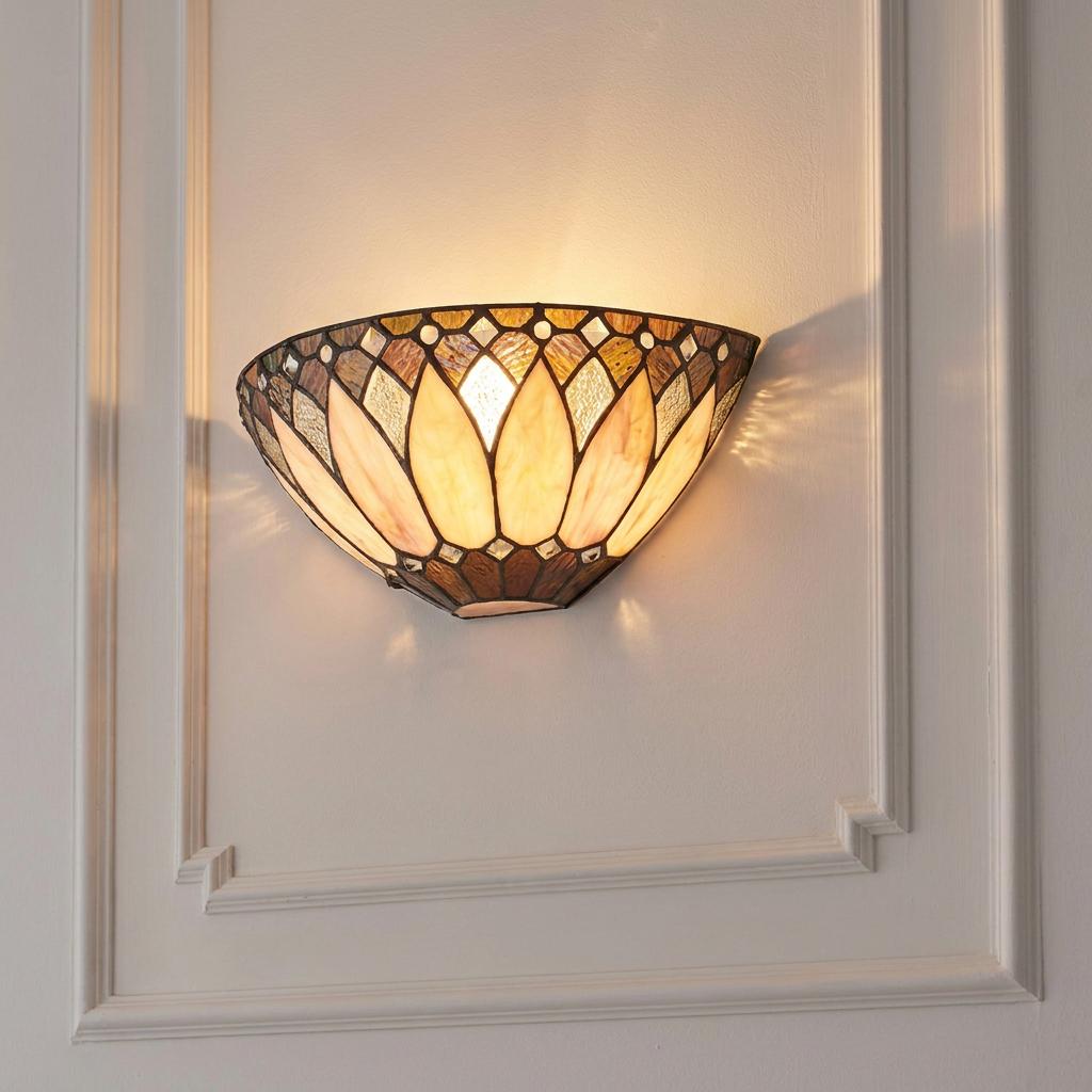 A warm-lit Tiffany-style wall sconce with a cream and amber stained glass shade mounted on a white paneled wall.