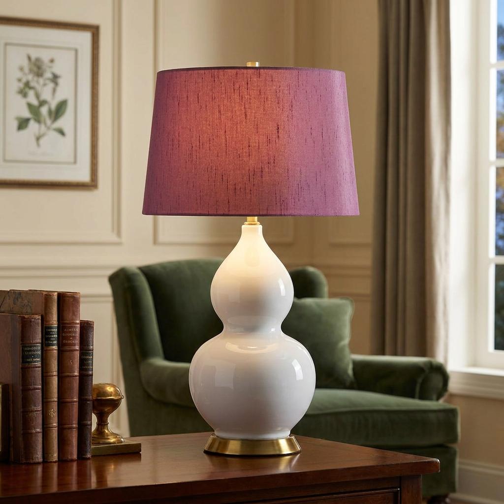White ceramic double-gourd table lamp with a textured purple shade on a wooden desk in a living room.