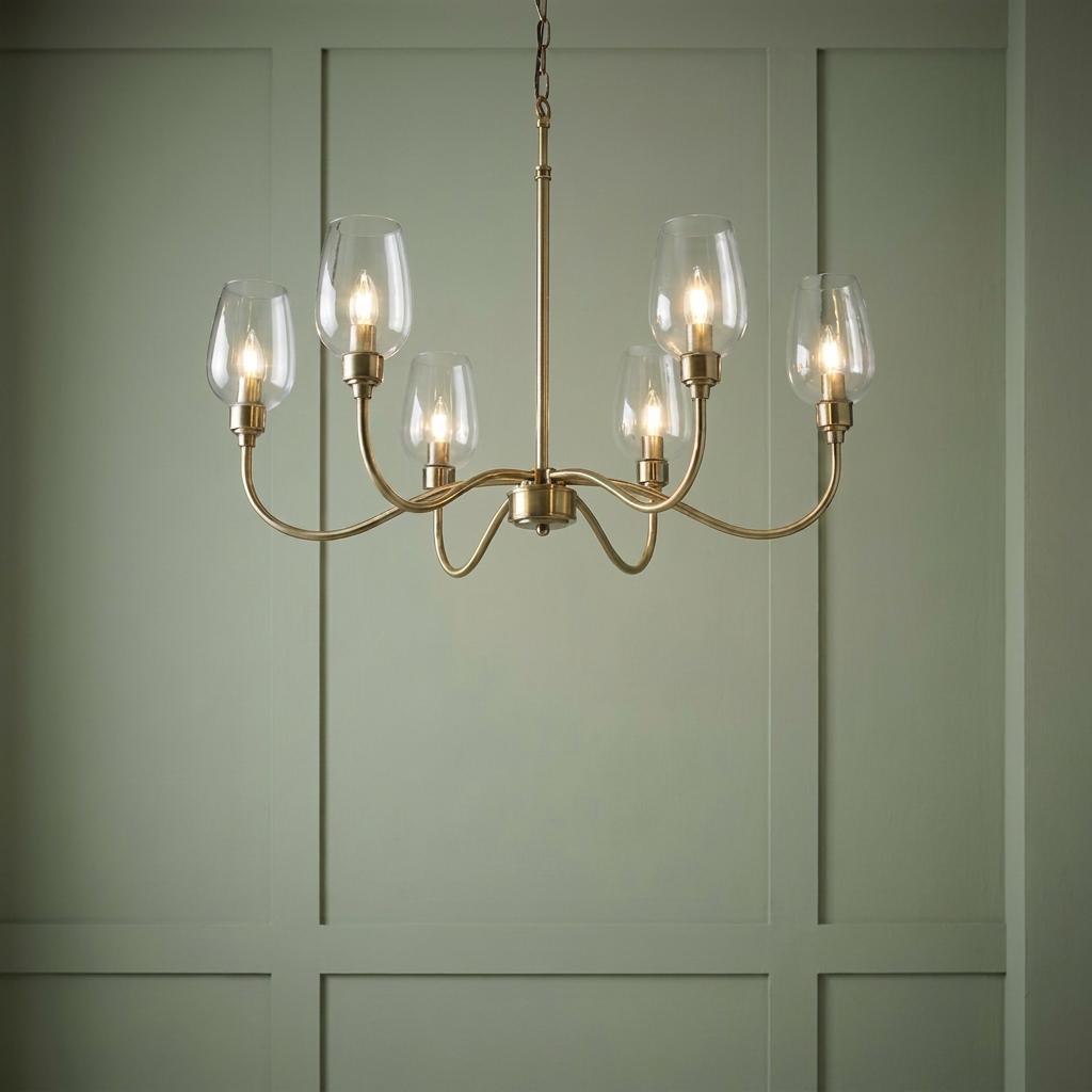 Six-light brass chandelier with clear glass tulip shades glowing against a sage green wood paneled wall.
