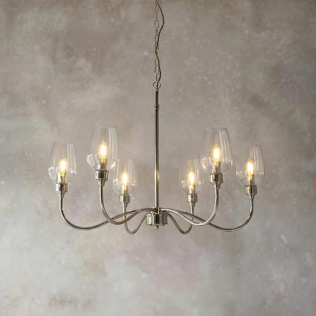 Art Deco nickel pendant with six curved arms and clear glass shades against a textured wall.