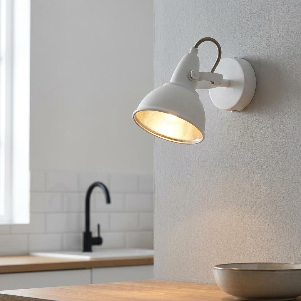 White wall-mounted spotlight with gold inner lining illuminating a modern kitchen countertop.
