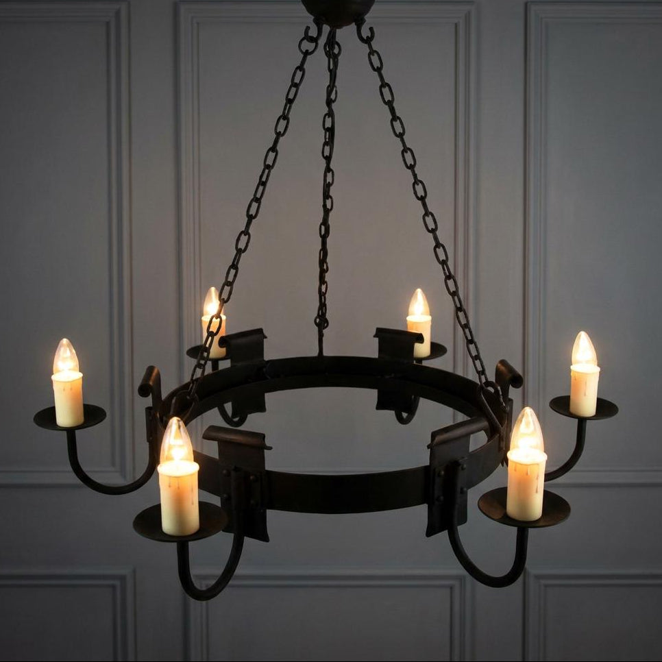 Six-arm black wrought iron hoop chandelier with lit candle-style bulbs hanging against a grey paneled wall.