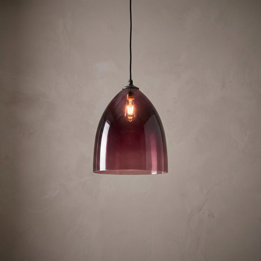 Large aubergine glass pendant light with a glowing bulb against a neutral textured wall.
