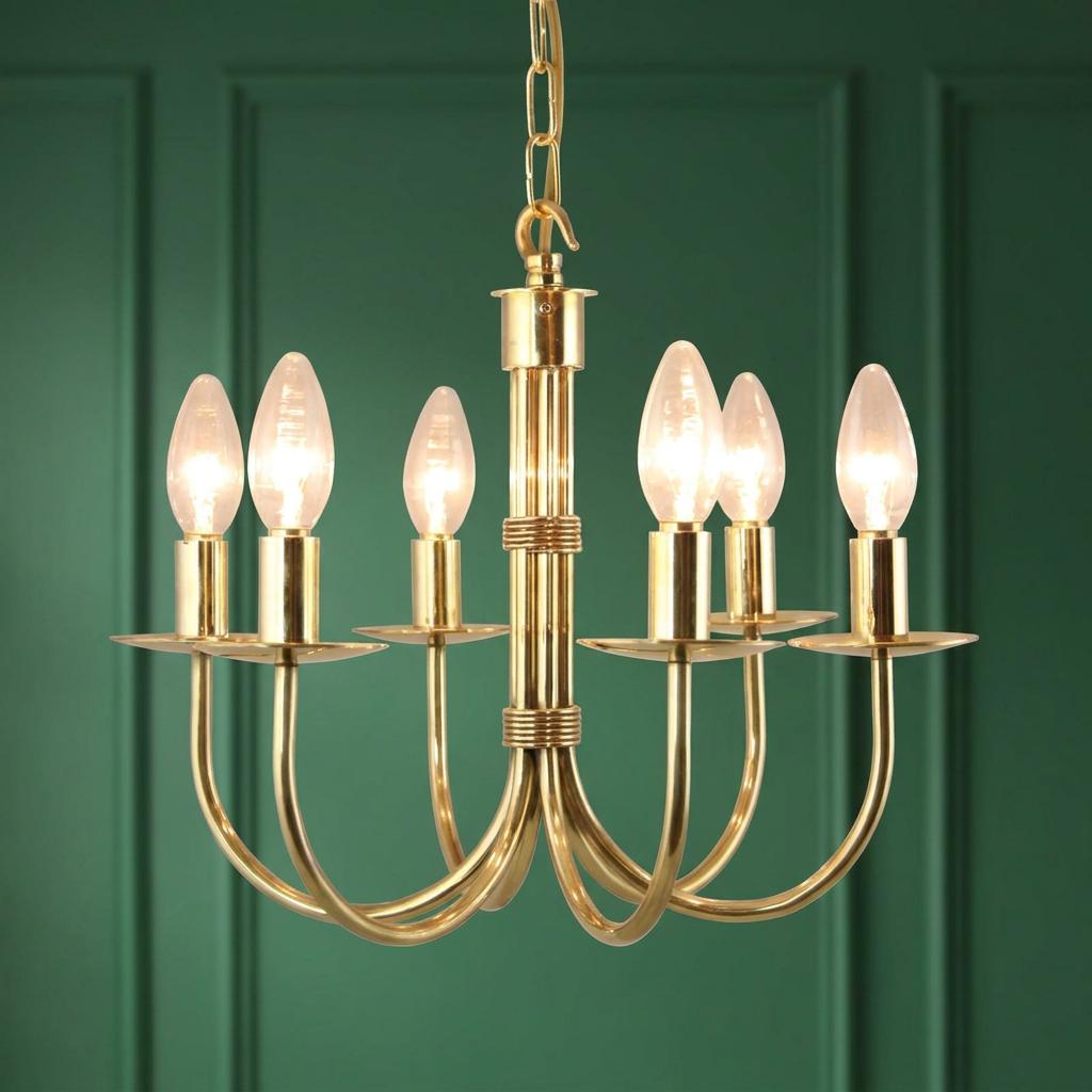 Polished brass 6-light chandelier with glowing candle bulbs against a dark green paneled wall.