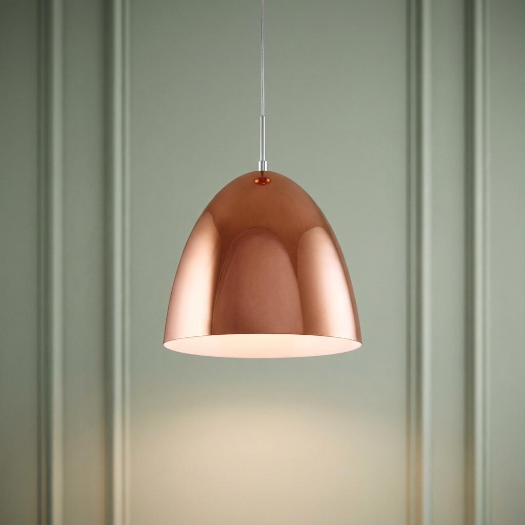 Polished copper dome pendant light hanging against a pale green panelled wall.