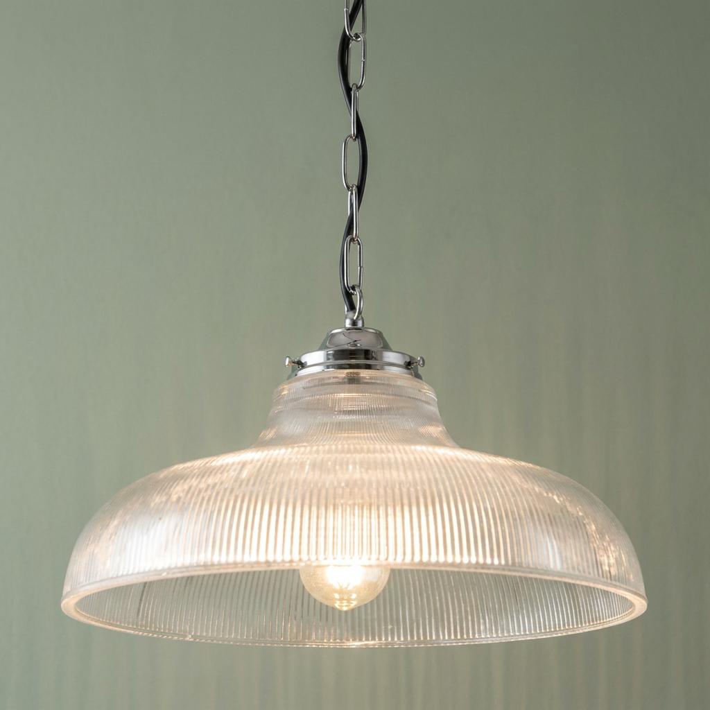 Traditional ceiling light with a ribbed clear glass dome shade and chrome chain hanging against a green wall.
