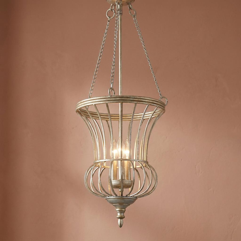 Silver-leaf three-light lantern pendant featuring a curved metal cage frame against a warm pink wall.