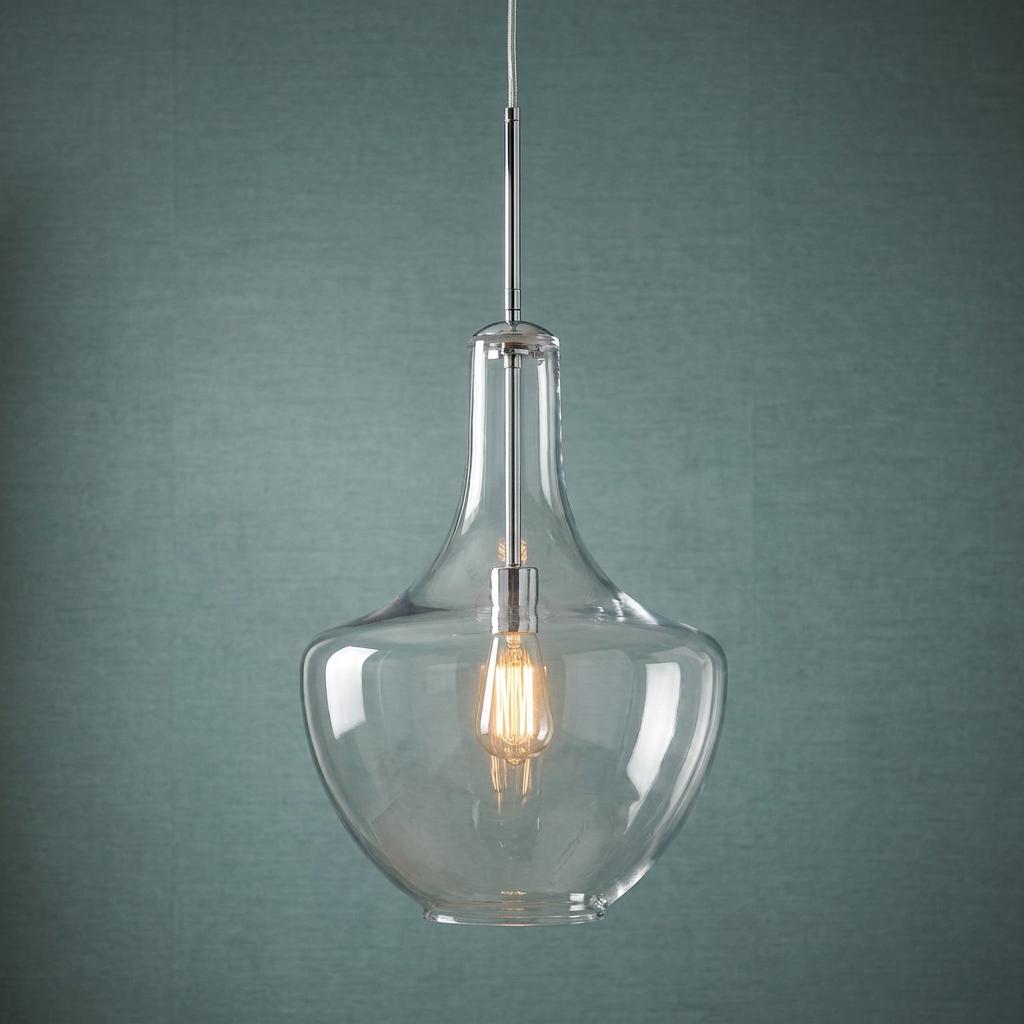Chrome pendant light with a clear glass shade and warm Edison bulb against a textured teal wall.