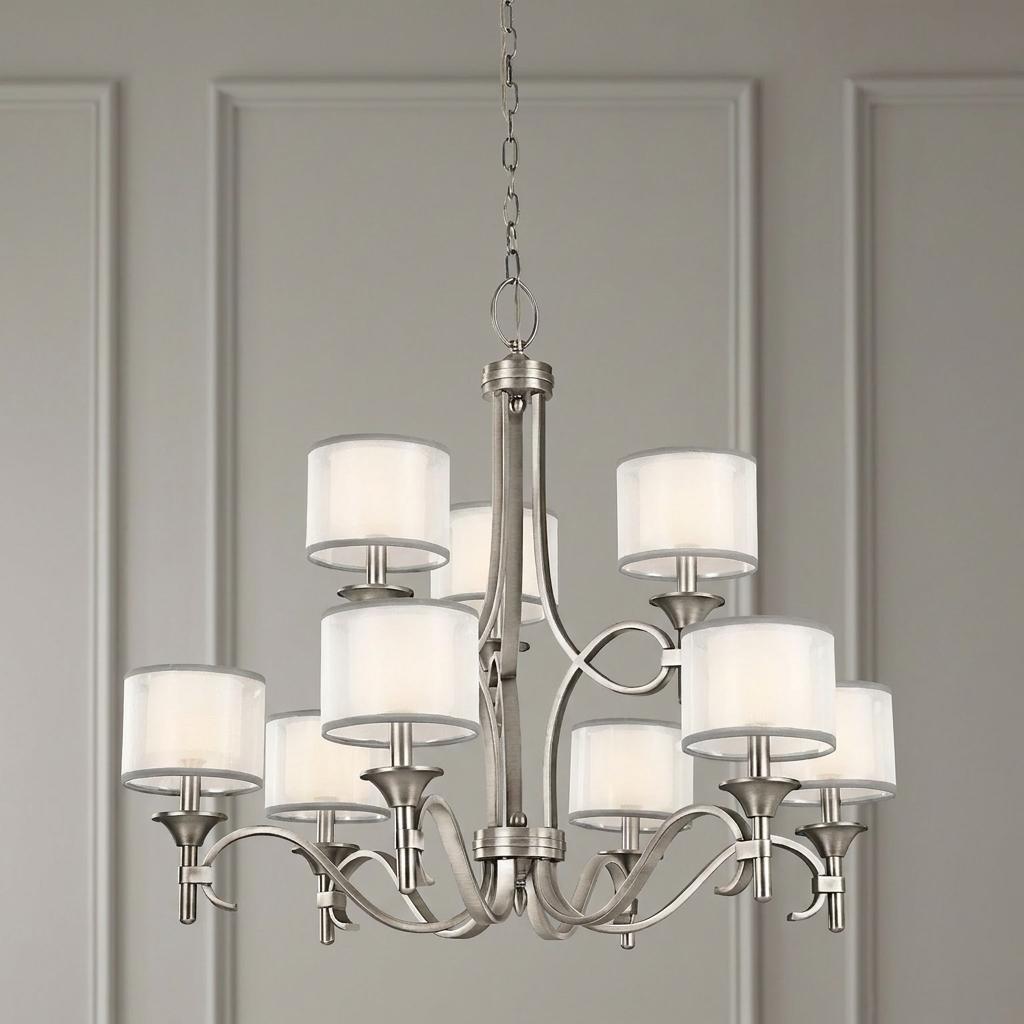 Nine-light antique pewter chandelier with white fabric shades hanging against a grey paneled wall.