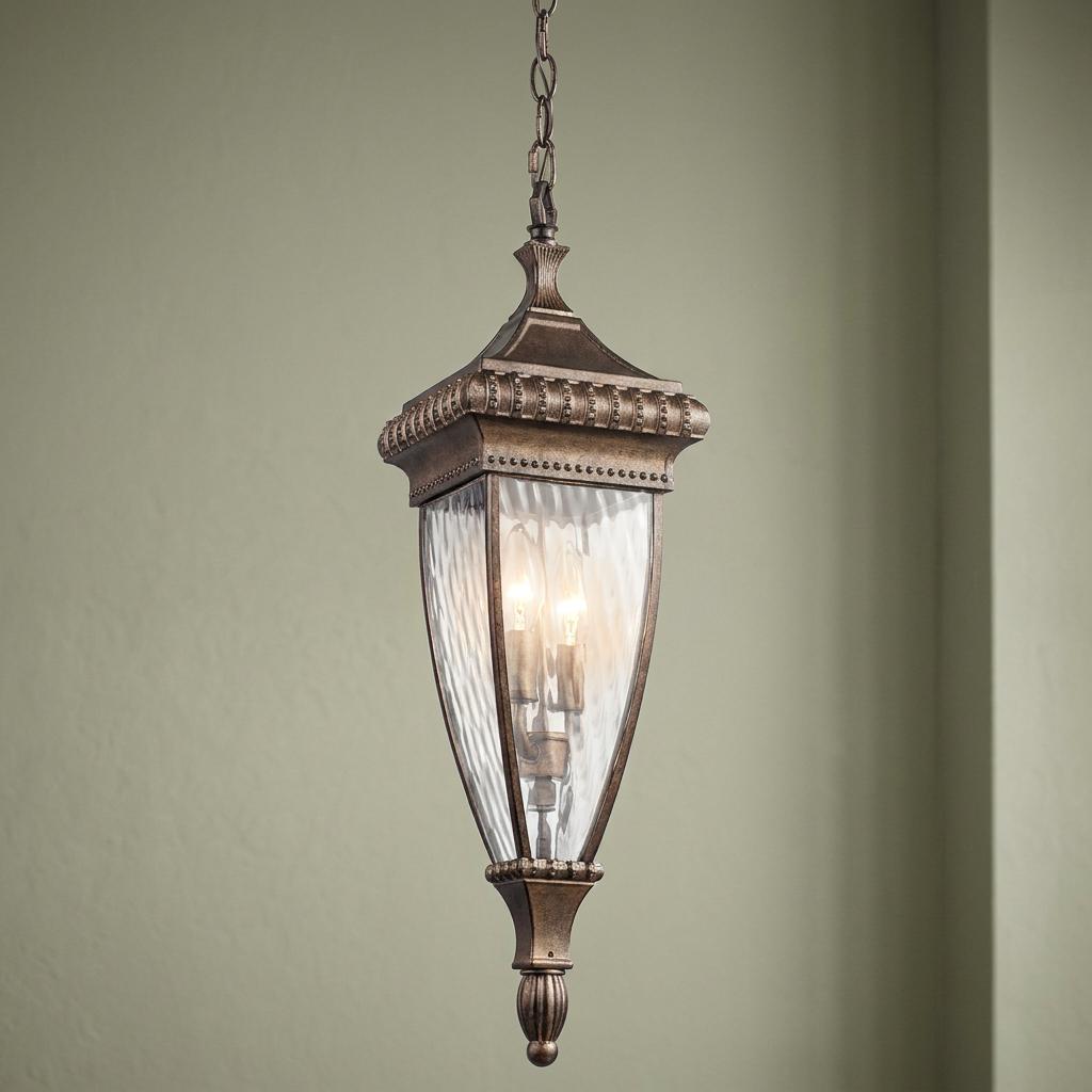 Ornate brushed bronze outdoor pendant light with rippled glass panels and a decorative lantern frame.