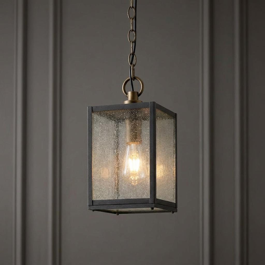 Lahden 1 light outdoor chain lantern with a black frame and seeded glass hanging against a dark wall.
