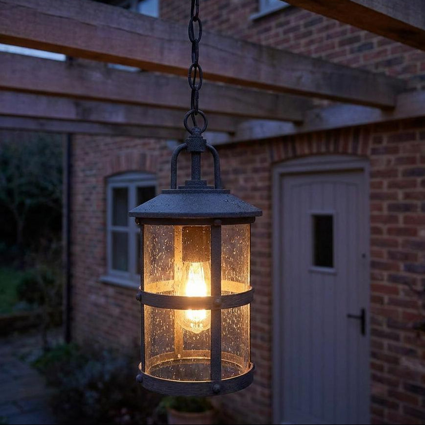 Lakehouse outdoor chain lantern with seeded glass and a warm bulb hanging from a wooden pergola at dusk.