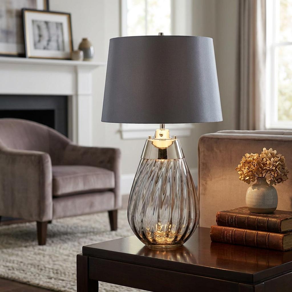 Lena small smoke glass table lamp with a grey shade on a dark wood side table in a contemporary living room.