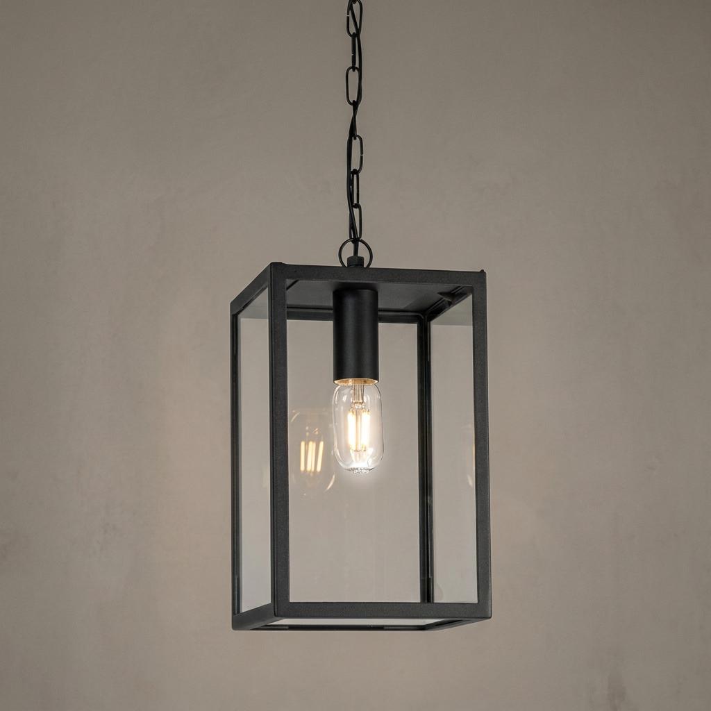 A rectangular black metal outdoor chain lantern with clear glass panes and a glowing LED bulb.
