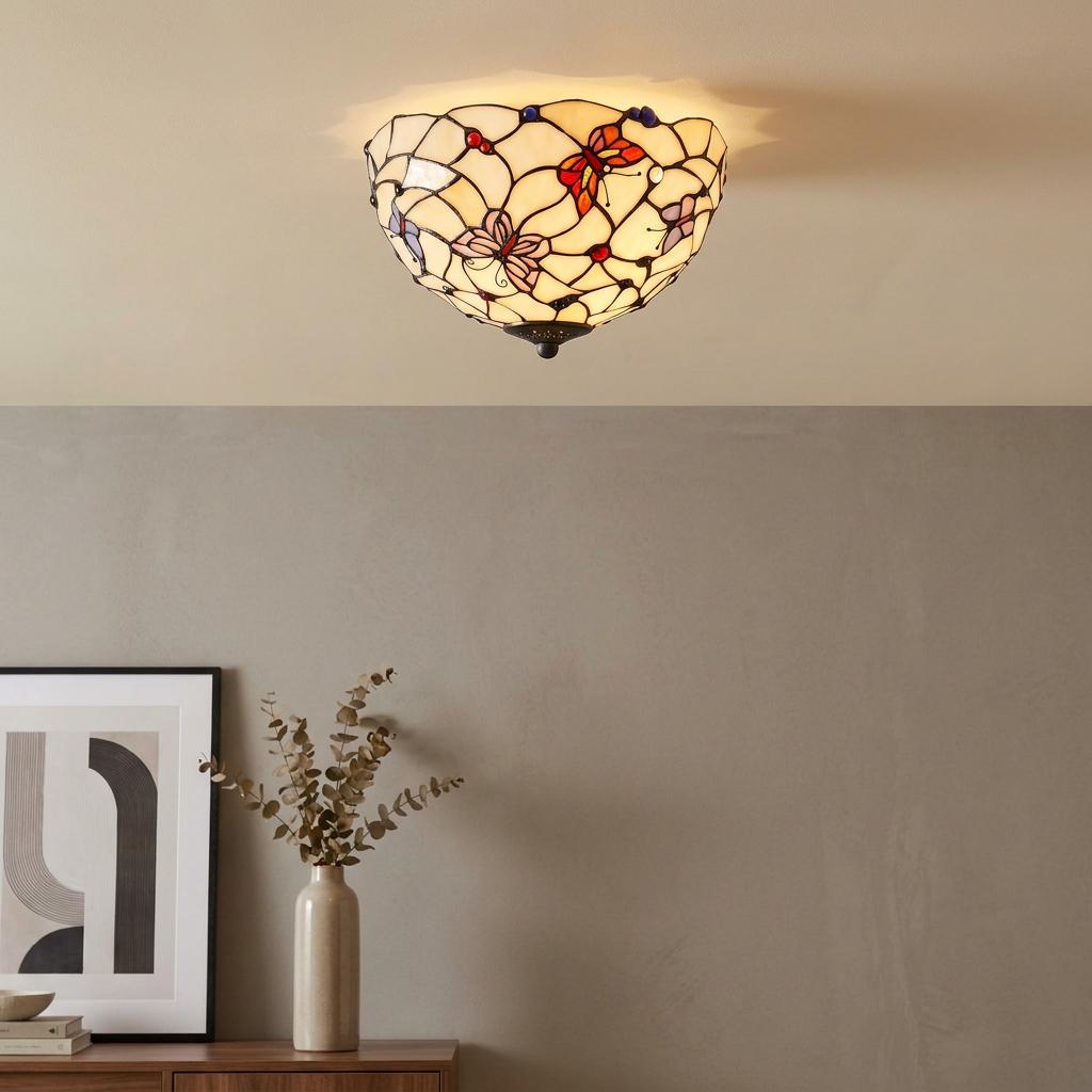 A flush-mounted Tiffany ceiling light with a butterfly design illuminates a room above a minimalist sideboard.