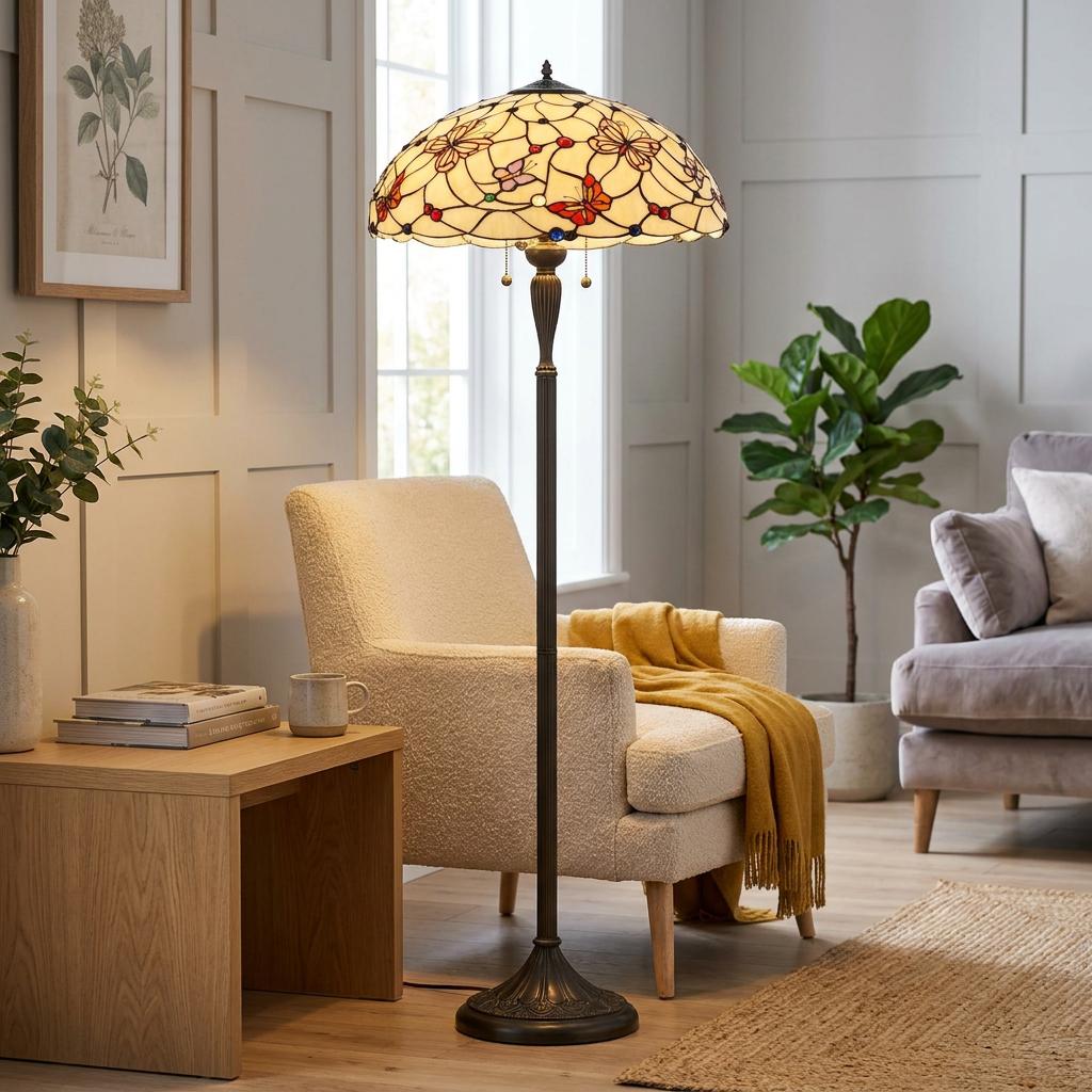 London Tiffany floor lamp with a butterfly patterned shade standing next to a cream armchair in a living room.