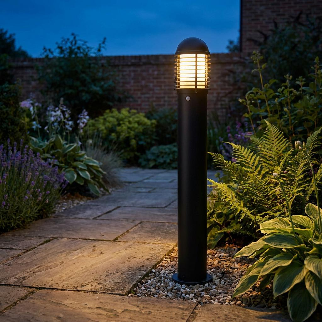 Black louvred bollard light illuminating a stone garden path at dusk.