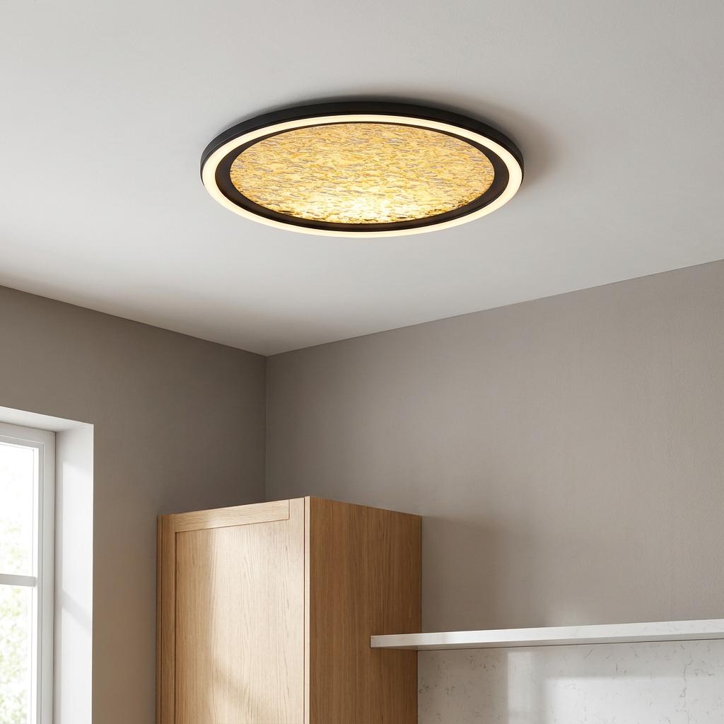 Circular flush ceiling light with a black rim and glowing textured center installed in a modern kitchen.