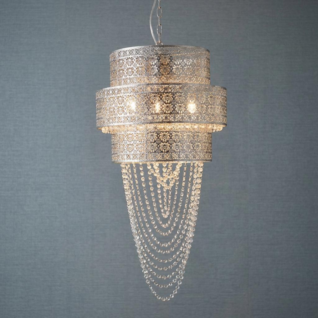 Lyra 12-light chrome pendant with perforated metal tiers and cascading crystal beads against a grey wall.