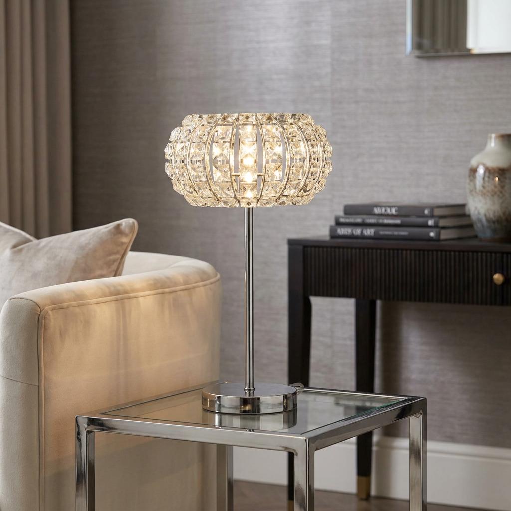 Marilyn 1 light chrome crystal glass table lamp on a glass side table in a modern living room setting.