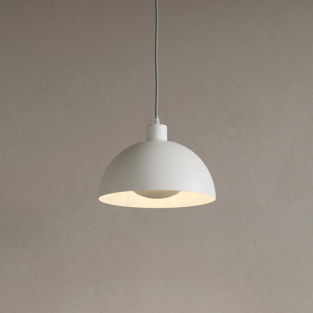 A cream-colored dome pendant light illuminated against a plain neutral background.
