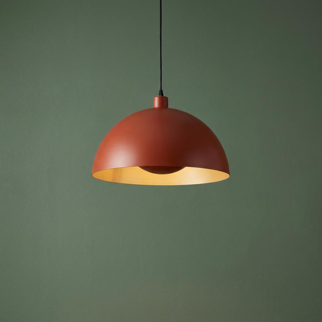 Industrial orange dome pendant light with a cream interior against a dark green background.