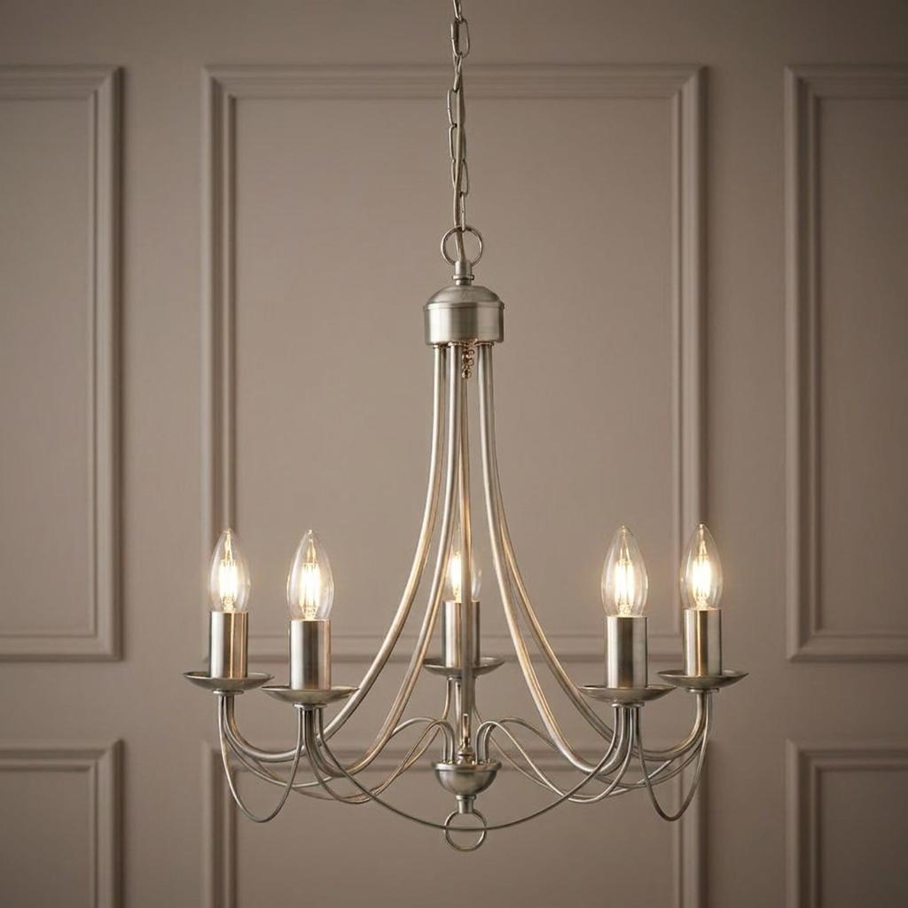 Five-light antique brass pendant chandelier with lit candle bulbs against a decorative panelled wall.