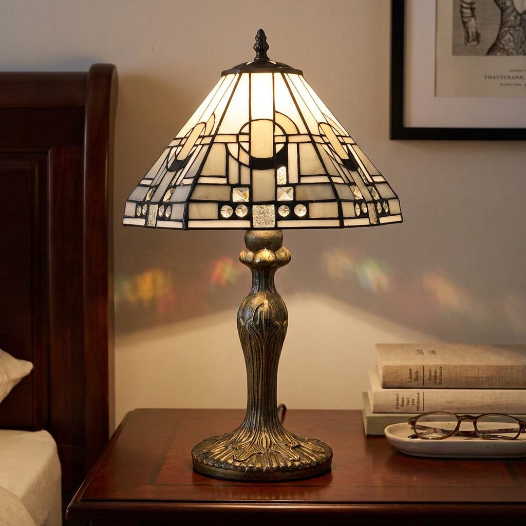 Art Deco Tiffany table lamp with a geometric white stained glass shade on a dark wood bedside table.