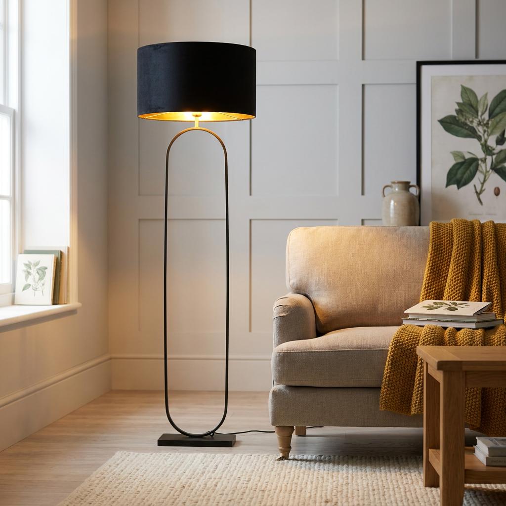 Modern matt black floor lamp with a black velvet shade and gold lining, standing beside a cozy armchair.