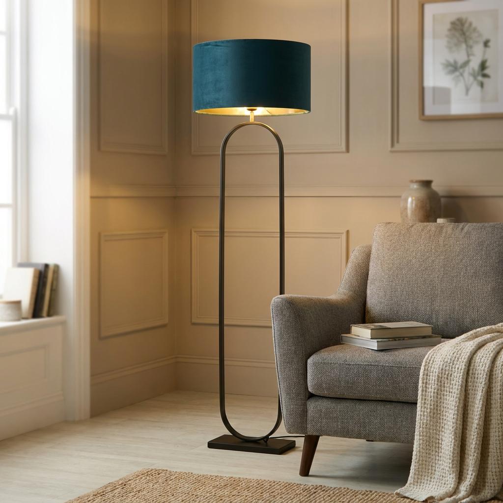 Matte black floor lamp featuring an oval frame and a teal velvet shade in a modern living room.