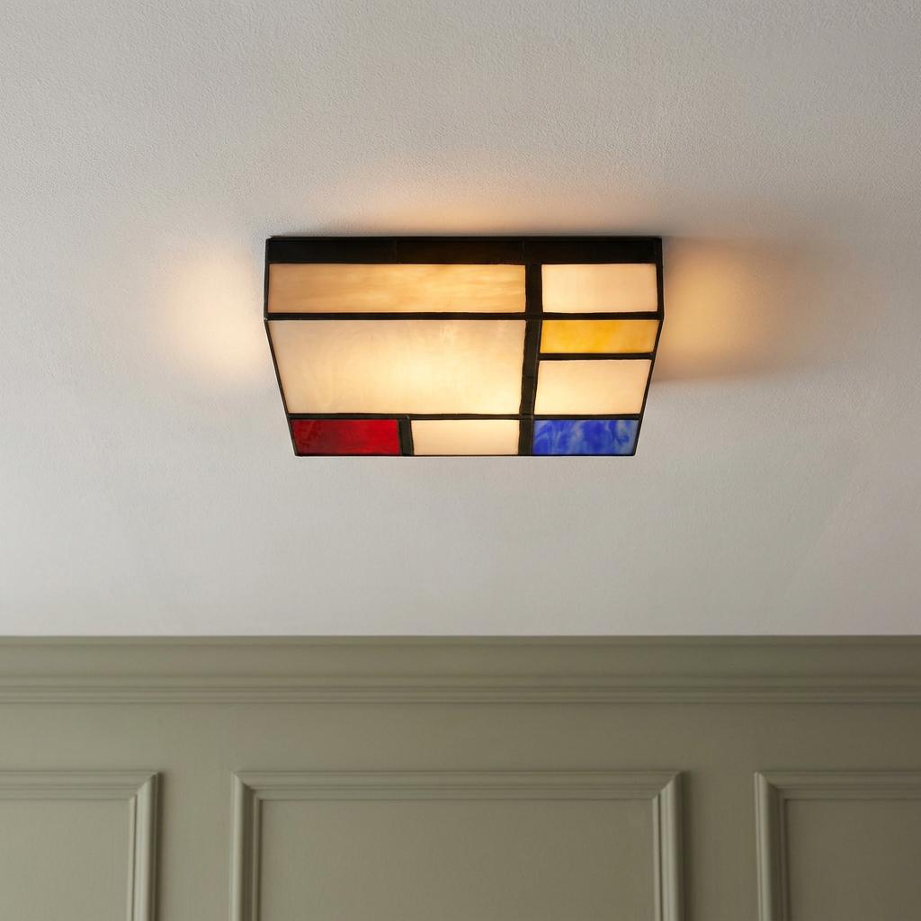 Mondriaan-style stained glass flush ceiling light with red, blue, and yellow panels glowing on a white ceiling.
