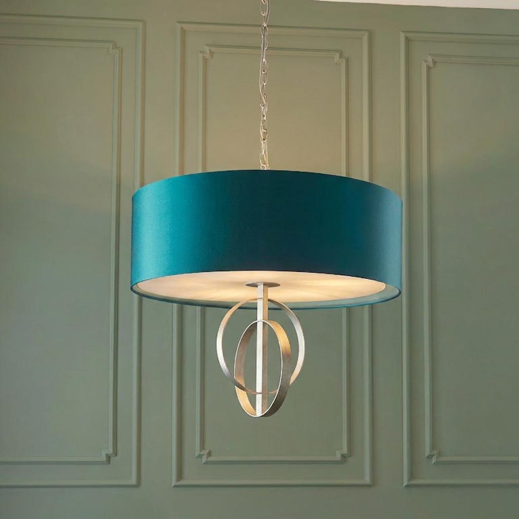 Norfolk extra large 5 light silver leaf pendant with a teal drum shade hanging against a green paneled wall.