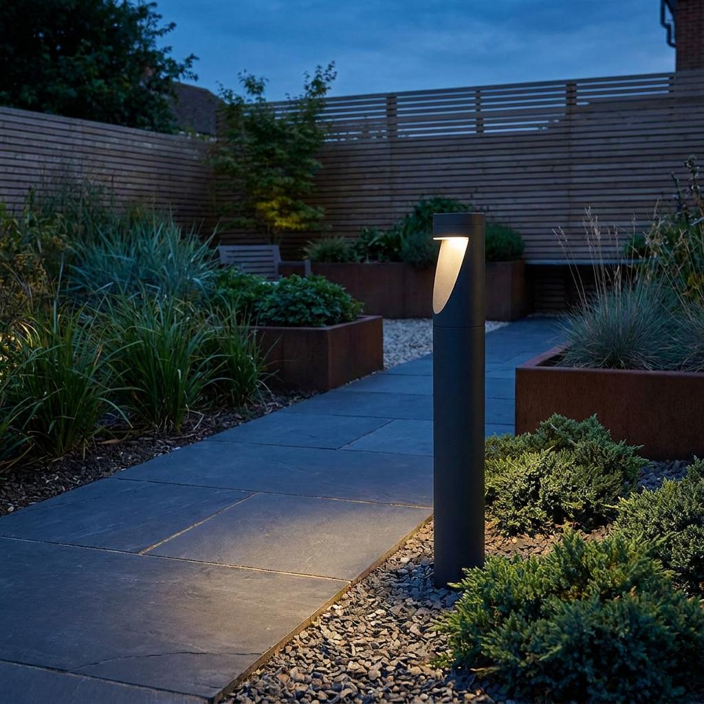 Graphite cylindrical bollard light illuminating a slate garden path at dusk.