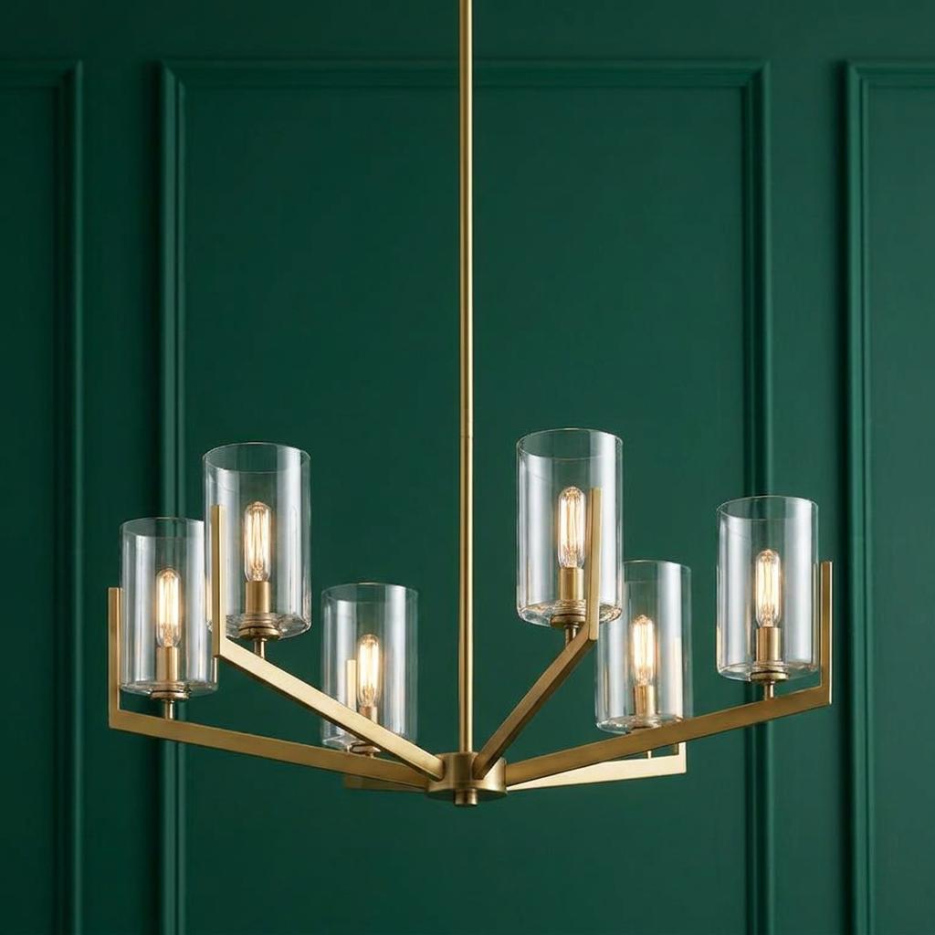 Nye 6-light brass chandelier with clear glass cylinder shades and Edison bulbs against a green paneled wall.