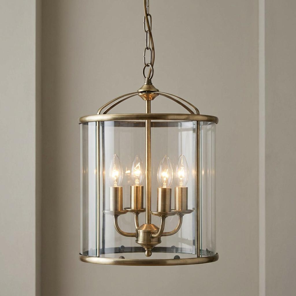 Antique brass four-light cylindrical lantern pendant with clear glass and a chain suspension.