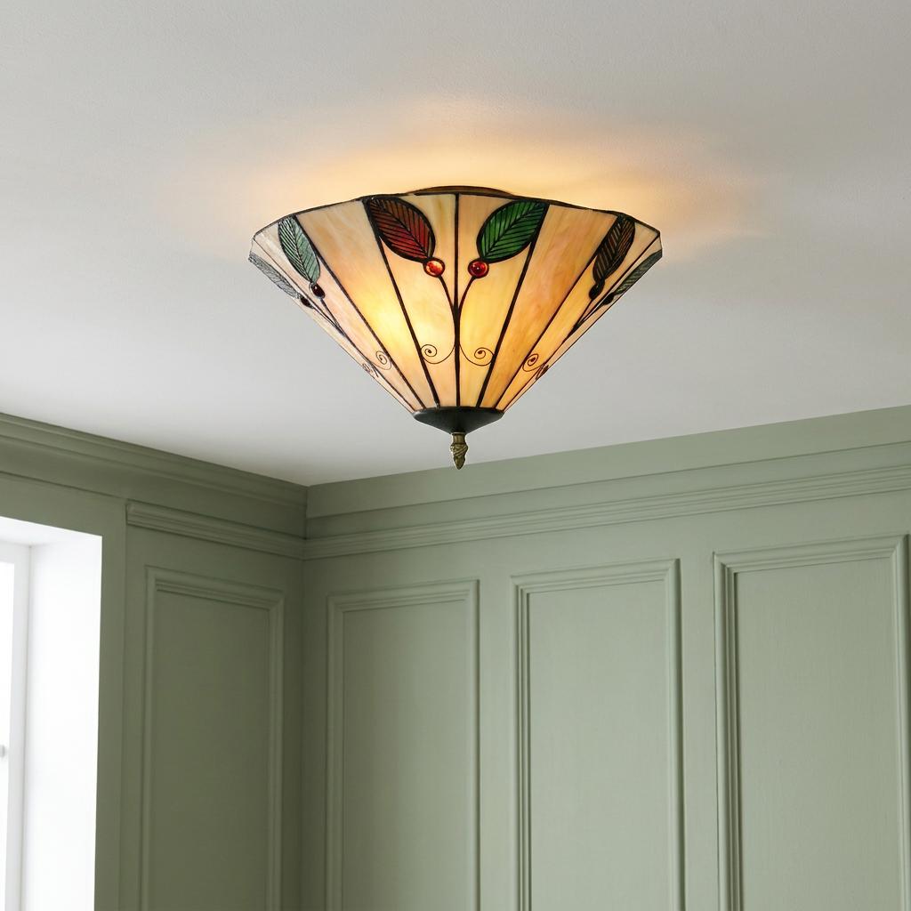 Tiffany-style flush ceiling light with leaf motifs mounted on a white ceiling in a room with green paneled walls.