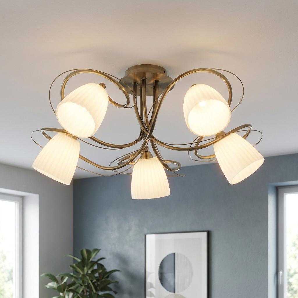 Antique brass 5-light ceiling fixture with white fluted glass shades on swirling arms in a modern living room.