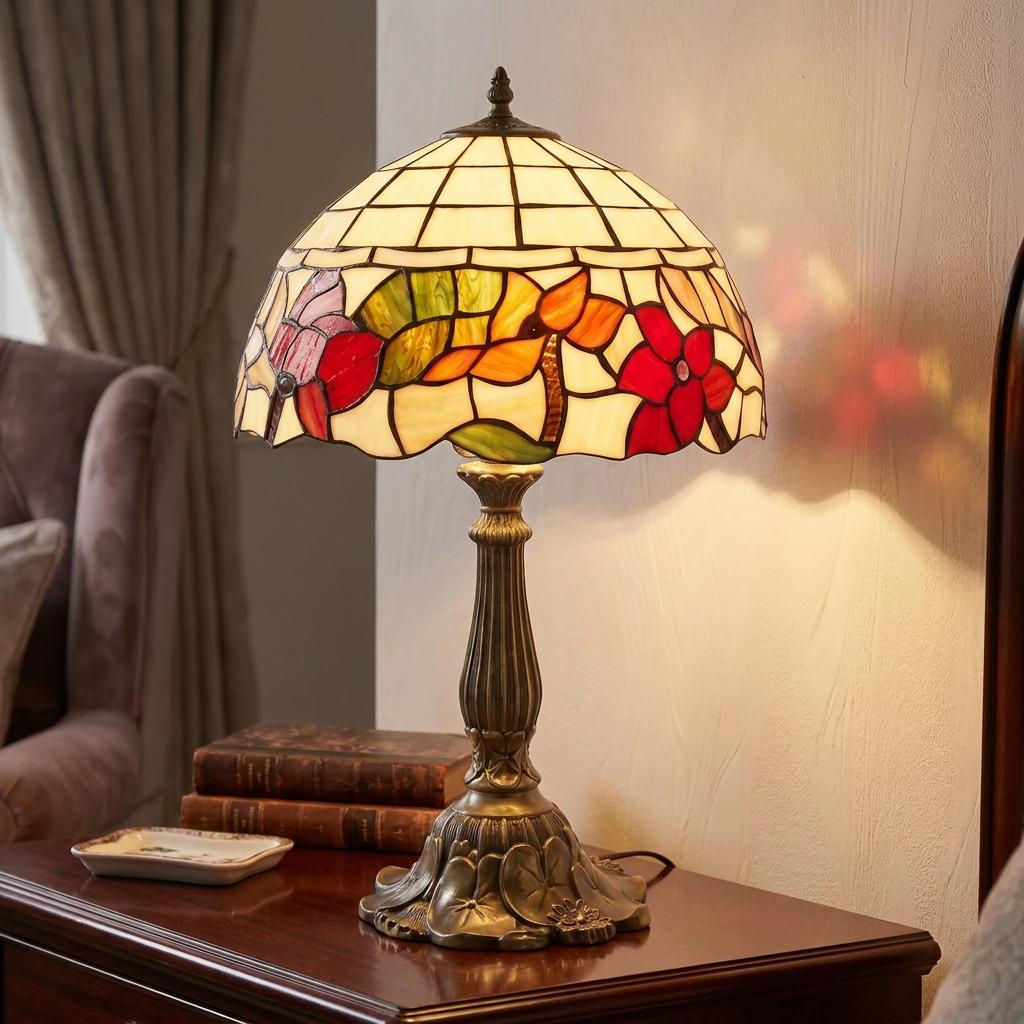 Tiffany-style table lamp with a floral stained glass shade illuminated on a wooden bedside table.