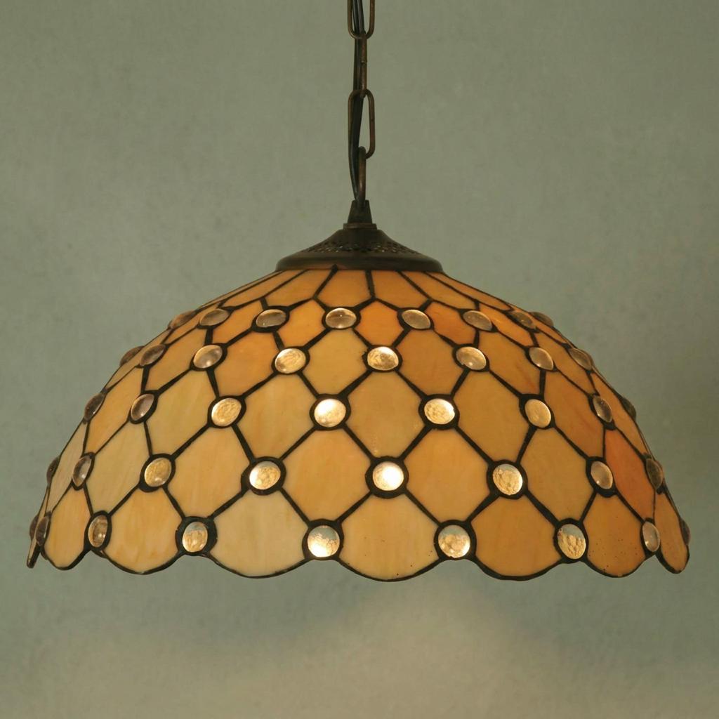 Jewel Tiffany pendant light with honey-toned stained glass, circular jewels, and diamond leading against a plain wall.