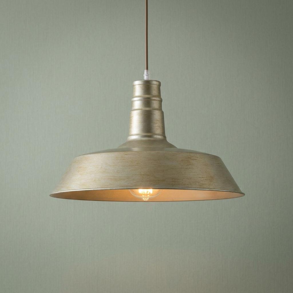 Industrial-style pendant light in champagne painted finish hanging against a sage green textured wall.